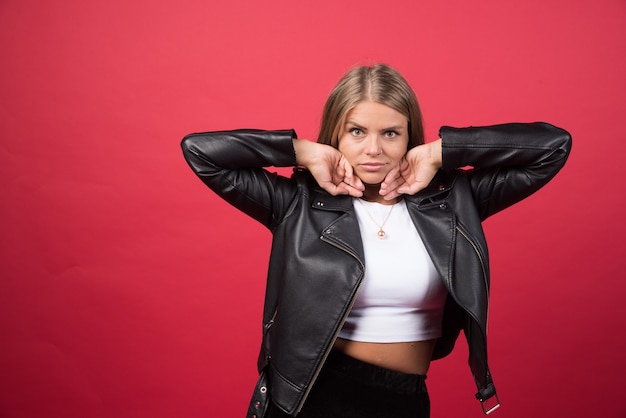 Young woman touching her face on a red wall