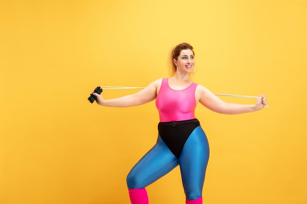 Free photo young woman training on yellow wall