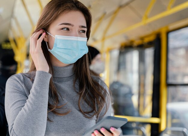 Young woman travelling by city bus using smartphone