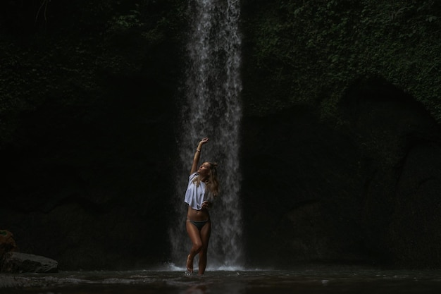 Free photo young woman travels around the island taking pictures at a waterfall