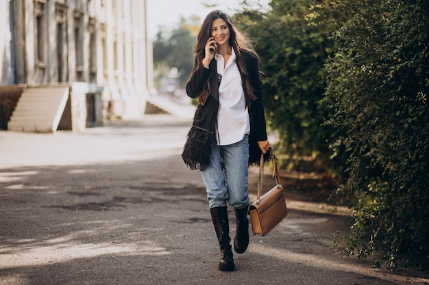 Young woman in trendy outfit walking in park