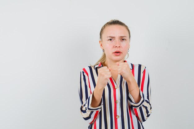 Young woman trying to fight with someone in striped blouse and looking angry