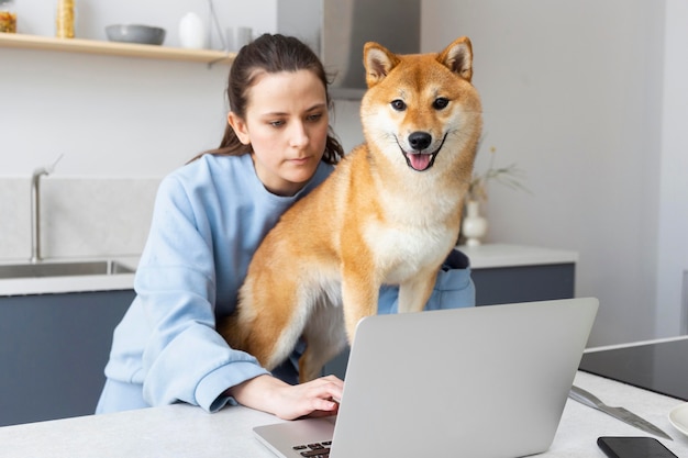 Free Photo young woman trying to work while her dog is distracting her