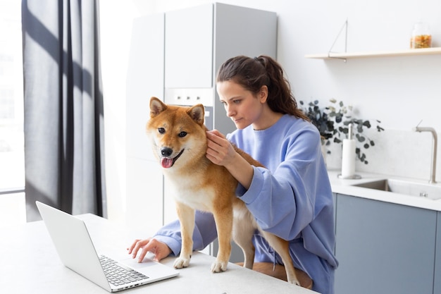 Free Photo young woman trying to work while her dog is distracting her