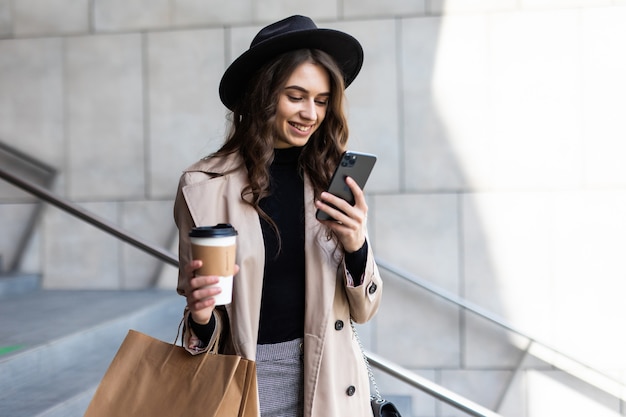 Young woman use of mobile phone and holding shopping bag in the street