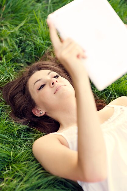 Young woman using digital tablet on meadow