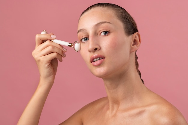 Young woman using face roller  side view