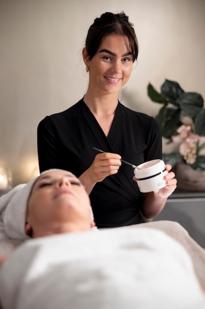 Free photo young woman using a face treatment on her client