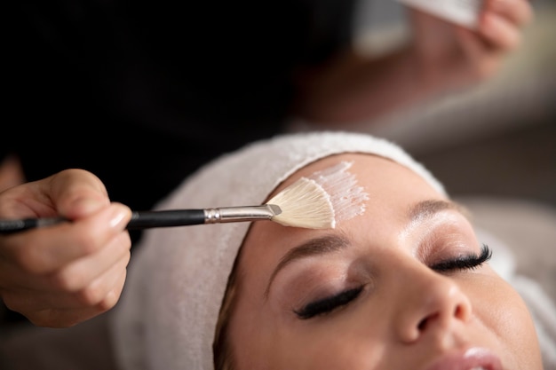 Young woman using a face treatment on her client