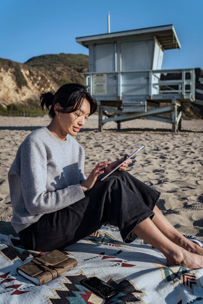 Young woman using her tablet at the beach