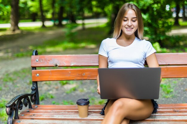 Young woman using a laptop on a bench in park