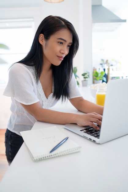 Young woman using laptop and notebook with pen for notes