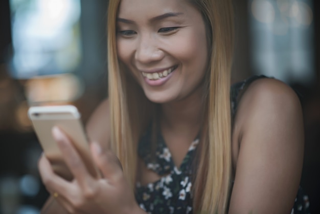 Free photo young woman using and looking at smartphone with feeling happy