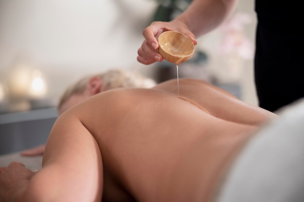 Free photo young woman using massage oil on her client