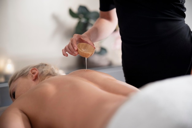 Free photo young woman using massage oil on her client