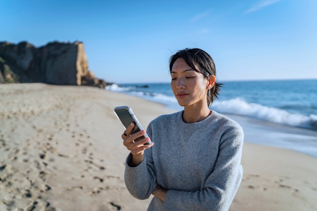 Young woman using smartphone at the beach