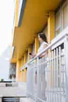 Free photo young woman using smartphone standing in balcony