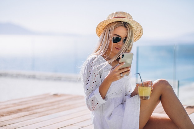 Free photo young woman on a vacation by the pool using phone