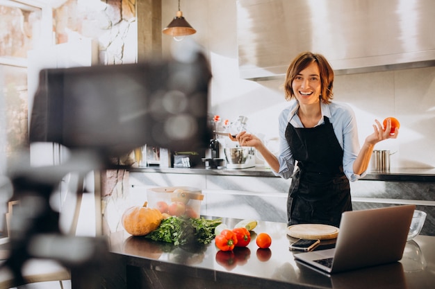 Young woman videoblogger cooking at the kitchen and filming