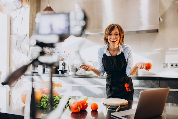 Young woman videoblogger cooking at the kitchen and filming