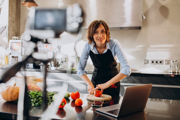 Young woman videoblogger cooking at the kitchen and filming