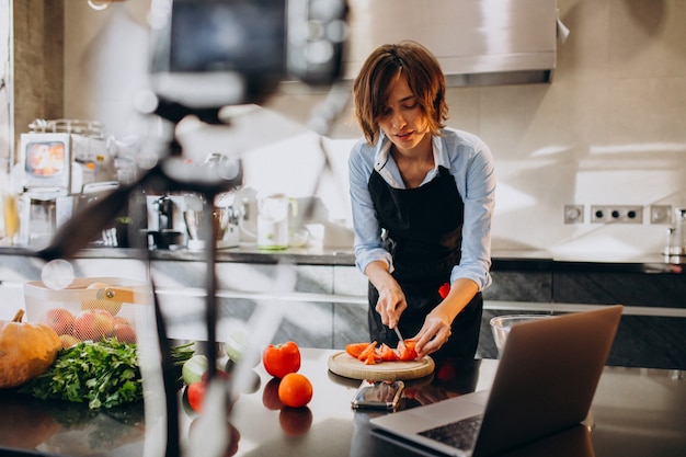 Young woman videoblogger cooking at the kitchen and filming