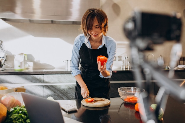 Free photo young woman videoblogger cooking at the kitchen and filming