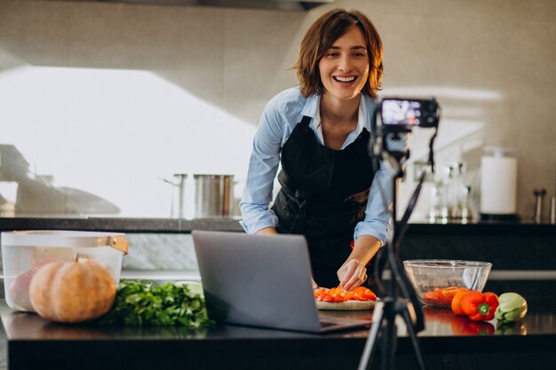 Young woman videoblogger cooking at the kitchen and filming