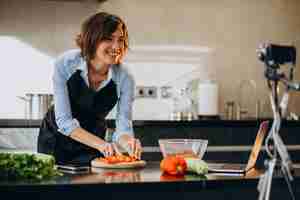 Free photo young woman videoblogger cooking at the kitchen and filming