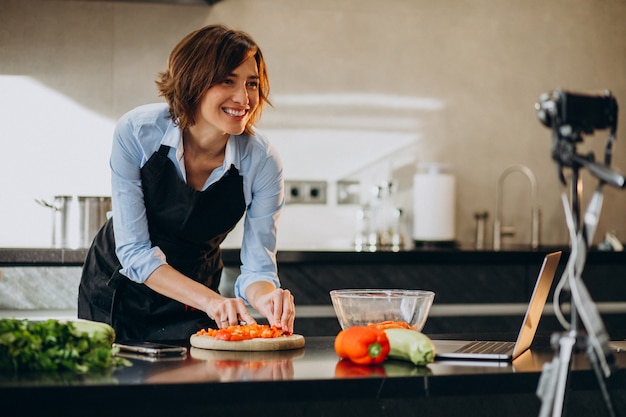 Young woman videoblogger cooking at the kitchen and filming