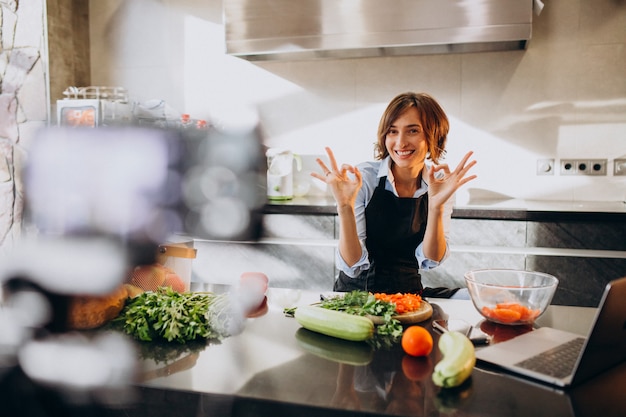 Young woman videoblogger cooking at the kitchen and filming