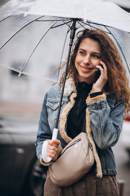 Young woman walking in the rain with umbrella