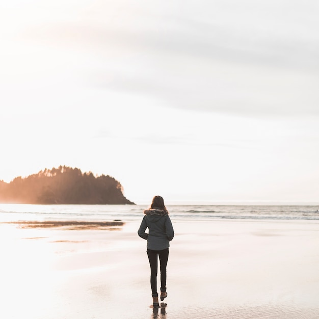 Free photo young woman walking towards sea