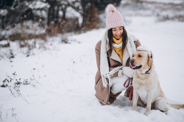 Young woman walking with her dog in a winter park