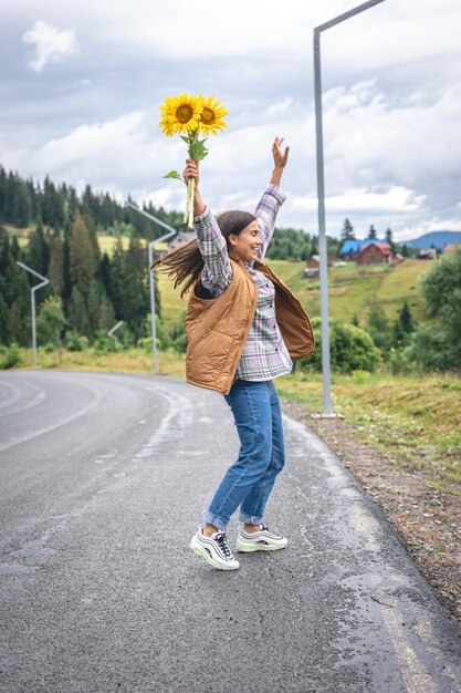 Free photo a young woman walks in the mountains with a bouquet of sunflowers