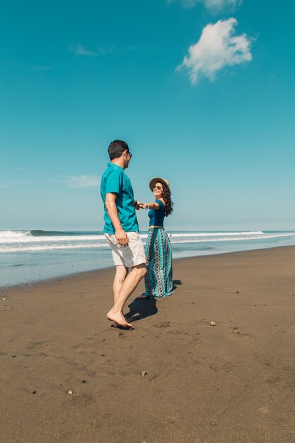 Young woman wanting her man follow to waterfront on beach