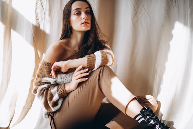 Young woman in a warm sweater sitting on ground