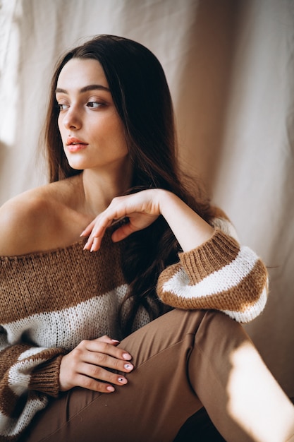 Young woman in a warm sweater sitting on ground