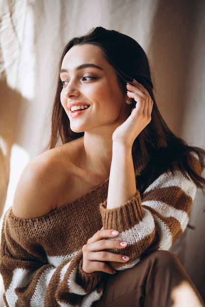 Young woman in a warm sweater sitting on ground