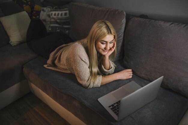 Young woman watching at laptop on sofa