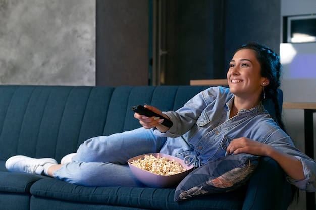 Free photo young woman watching streaming service at home