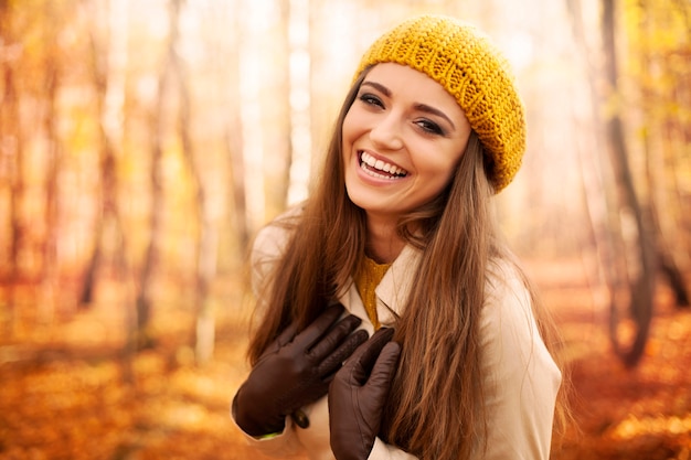 Young woman wearing autumn clothes laughing in park