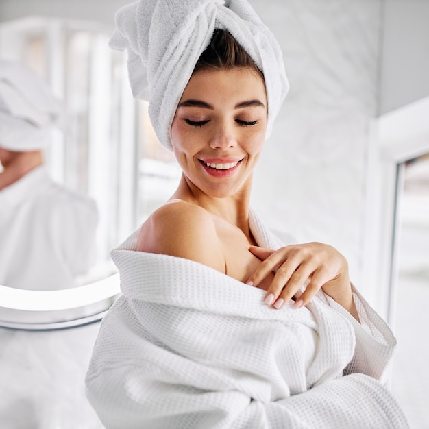 Young woman wearing a bathrobe and a towel on her hair