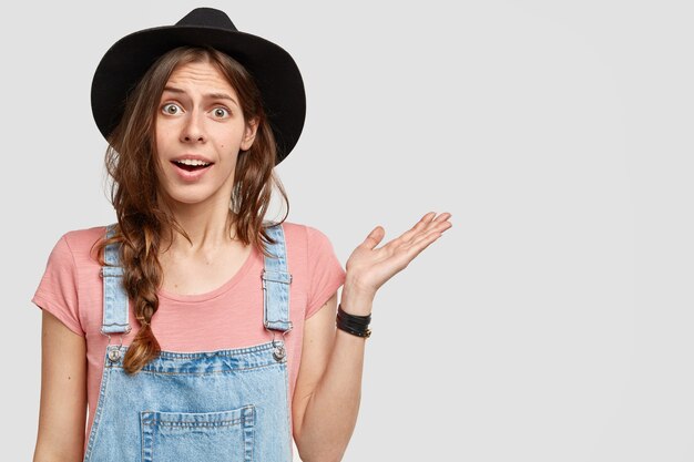 Young woman wearing big hat and overalls