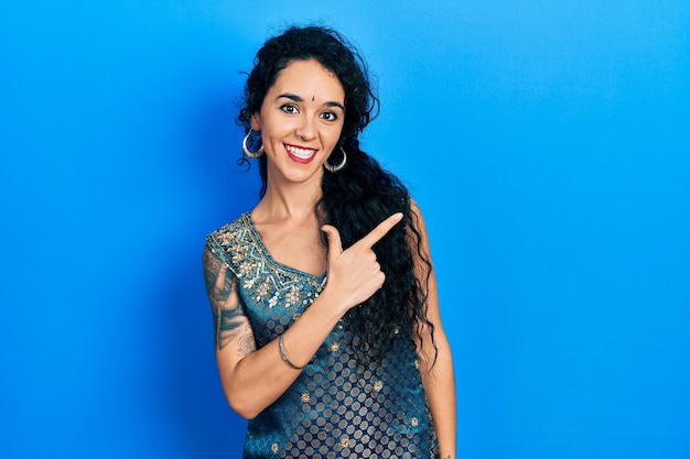 Free Photo young woman wearing bindi and traditional kurta dress cheerful with a smile of face pointing with hand and finger up to the side with happy and natural expression on face