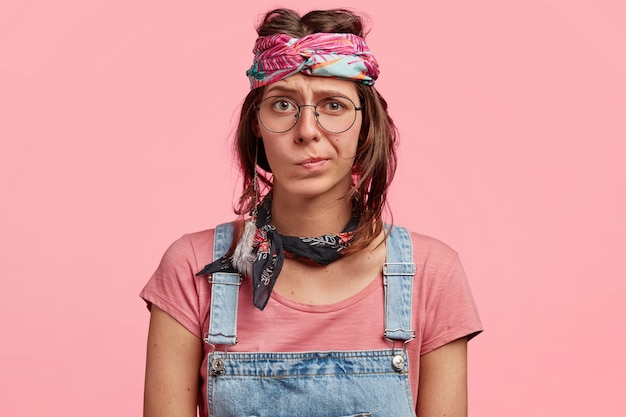 Young woman wearing colorful headband and denim overalls