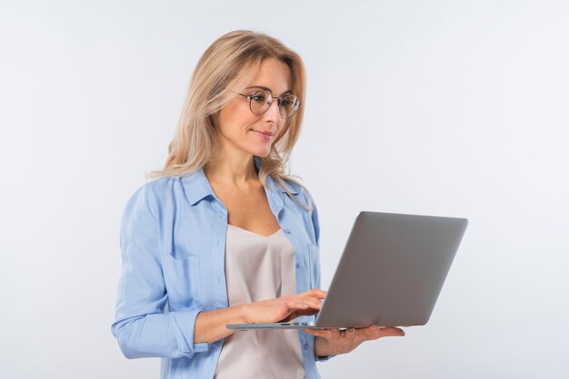 Young woman wearing eyeglasses using laptop against white background