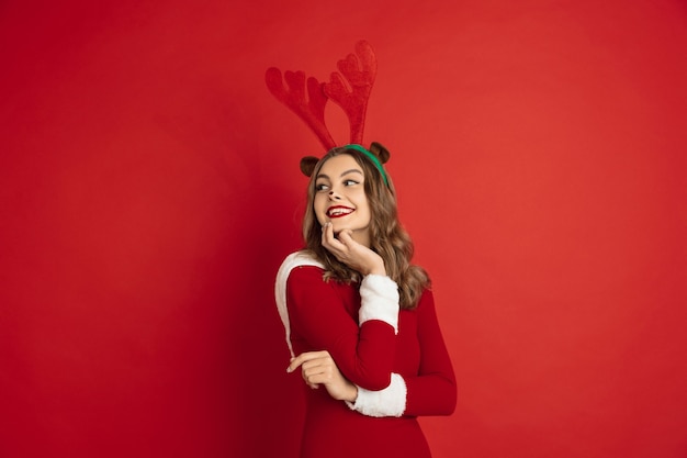 Free Photo young woman wearing a santa dress on red background