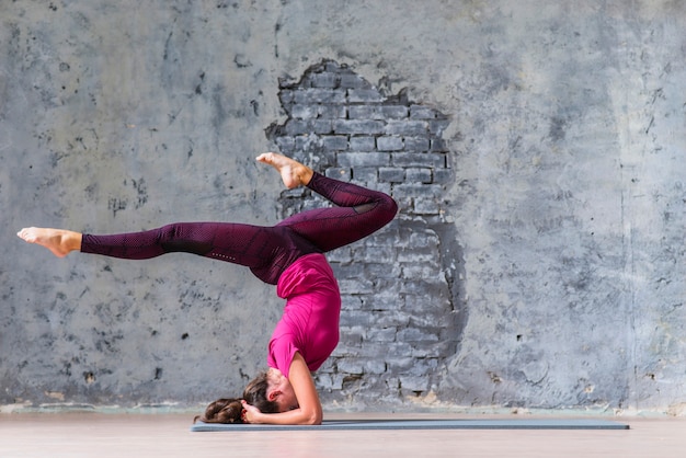 Free photo young woman wearing sportswear working out against grey wall