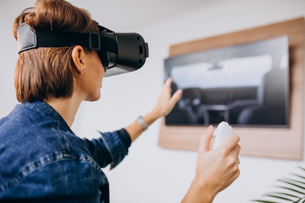 Free photo young woman wearing vr glasses and playing virtual game using remote